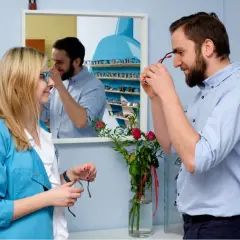 Optometrysta pomaga kobiecie dobrać okulary, być może w ramach terapii na daltonizm.