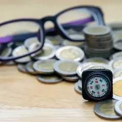 Okulary, monety i kompas symbolizują drogę do uzyskania dofinansowania do okularów.