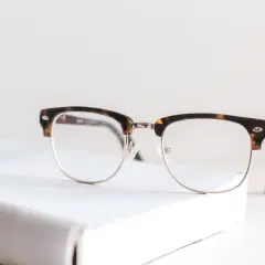 Okulary w stylu retro na białej książce. Nawet najmniejsza wada wzroku może wymagać takiego wsparcia.