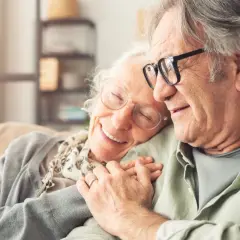 Szczęśliwi seniorzy, których wzrok poprawiła refundacja okularów dla emeryta. Czułe objęcia i uśmiech.