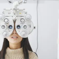 Kobieta z foropterem na twarzy, badana przez optometrystę. Ortoptysta ocenia jej wzrok.