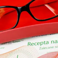 Okulary w etui i dokument z napisem "Recepta na okulary". Ważna recepta to klucz do dobrego widzenia.