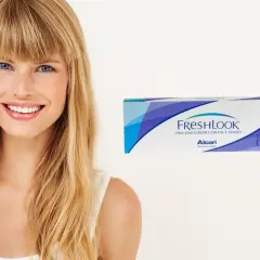 Uśmiechnięta blondynka z niebieskimi oczami obok pudełka soczewek FreshLook, które podkreślają kolor oczu.
