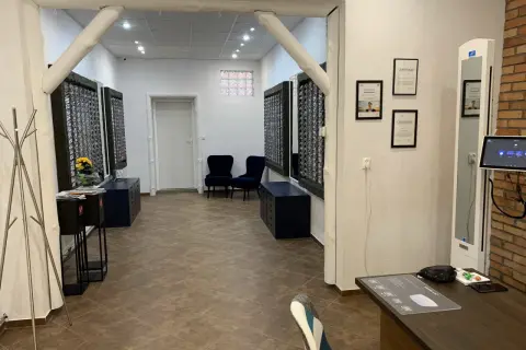 Wnętrze salonu optycznego, gdzie panuje strefa dobrego widzenia. Widać tu stojaki z okularami, wygodne fotele i certyfikaty.