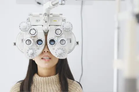 Kobieta z foropterem na twarzy, badana przez optometrystę. Ortoptysta ocenia jej wzrok.
