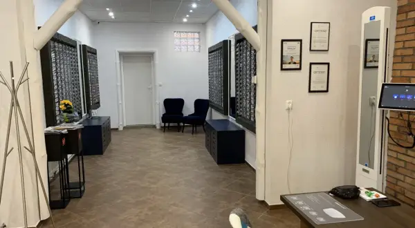 Wnętrze salonu optycznego, gdzie panuje strefa dobrego widzenia. Widać tu stojaki z okularami, wygodne fotele i certyfikaty.