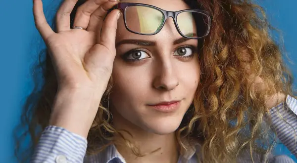Kobieta z burzą rudych loków poprawia okulary. Zastanawia się, jakie fotochromy wybrać, by pasowały do jej stylu.