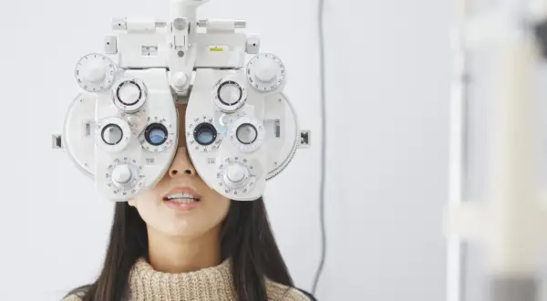Kobieta z foropterem na twarzy, badana przez optometrystę. Ortoptysta ocenia jej wzrok.