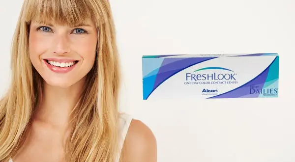 Uśmiechnięta blondynka z niebieskimi oczami obok pudełka soczewek FreshLook, które podkreślają kolor oczu.