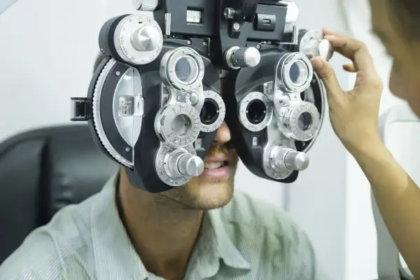 Badanie wzroku. Nie noszenie okularów skutki mogą być poważne. Optometrysta reguluje refraktorem.