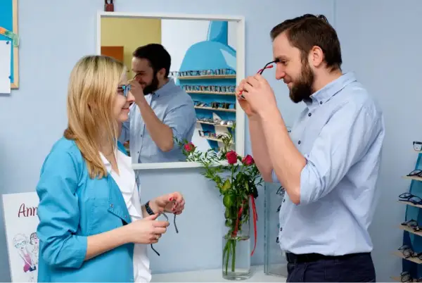 Optometrysta pomaga kobiecie dobrać okulary, być może w ramach terapii na daltonizm.