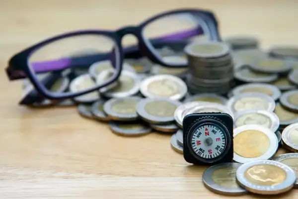 Okulary, monety i kompas symbolizują drogę do uzyskania dofinansowania do okularów.