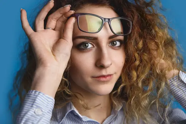 Kobieta z burzą rudych loków poprawia okulary. Zastanawia się, jakie fotochromy wybrać, by pasowały do jej stylu.